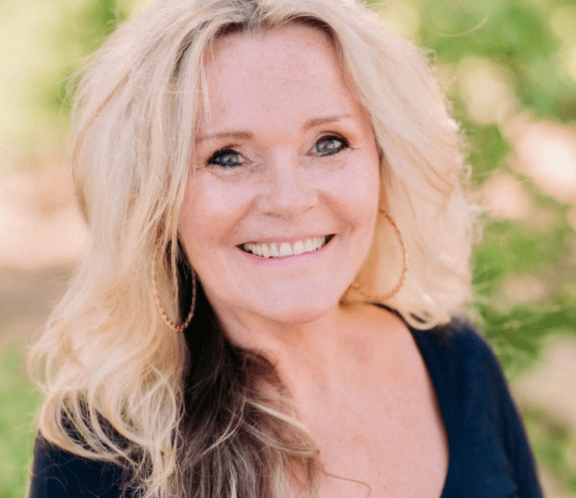 A woman with long blonde hair smiling for the camera.