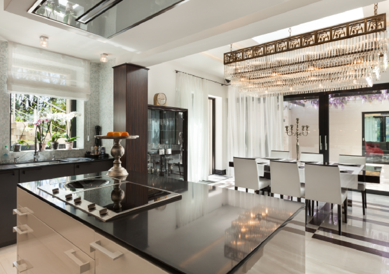 A large kitchen with black counter tops and white chairs.