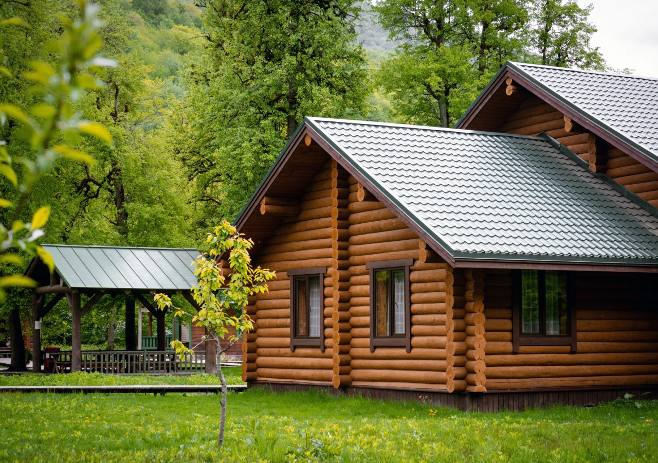 A log cabin with a metal roof and green grass.